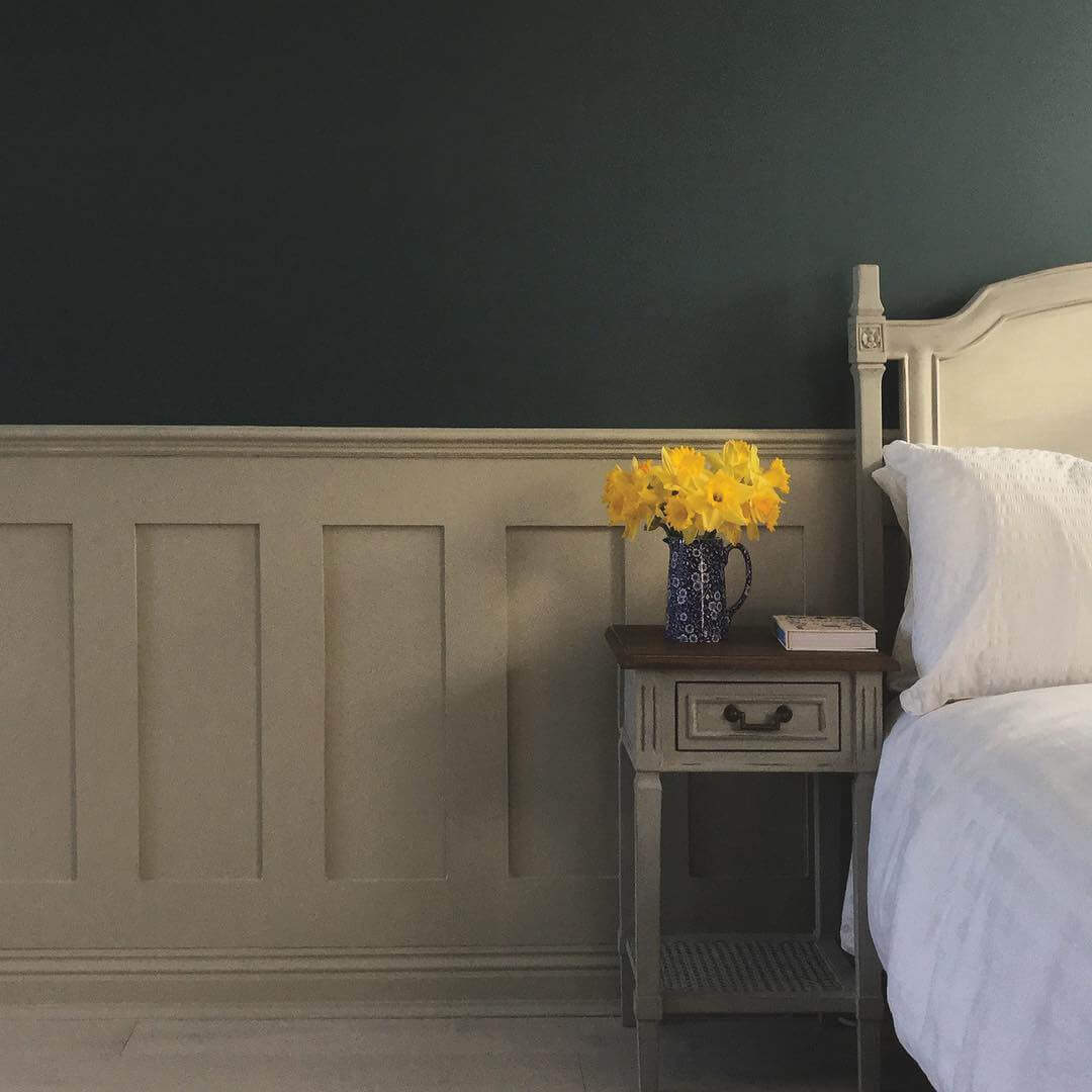 Bedroom with a nightstand featuring Edwardian MDF Wall Panelling and a vase of yellow flowers against a dark wall.